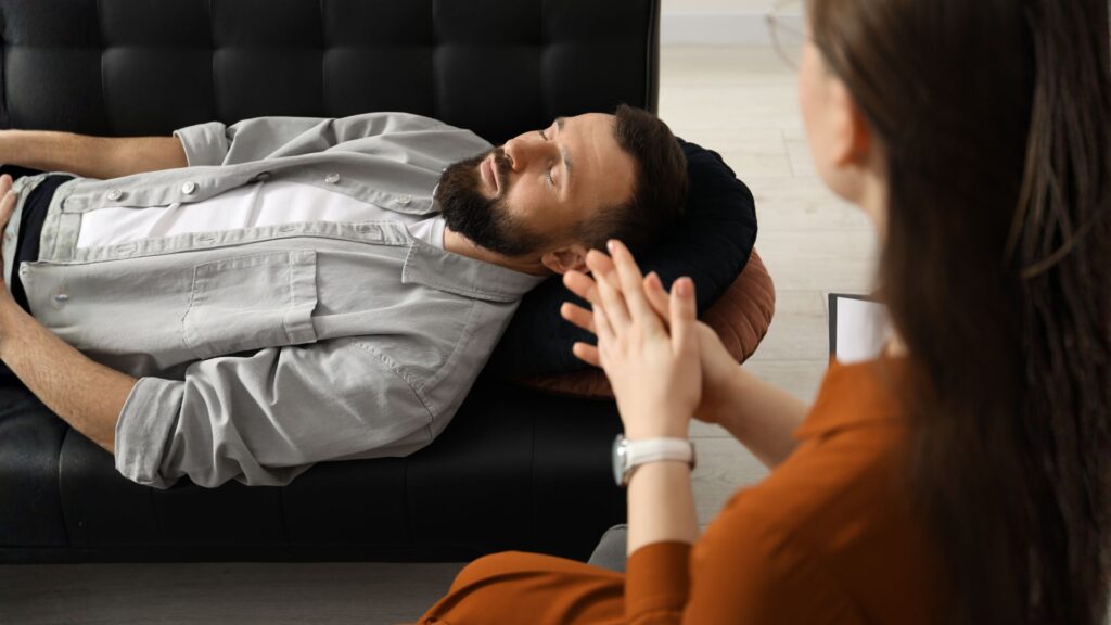 Pacjent leży na kanapie, wprowadzany jest w trans hipnotyczny, ma zamknięte oczy.